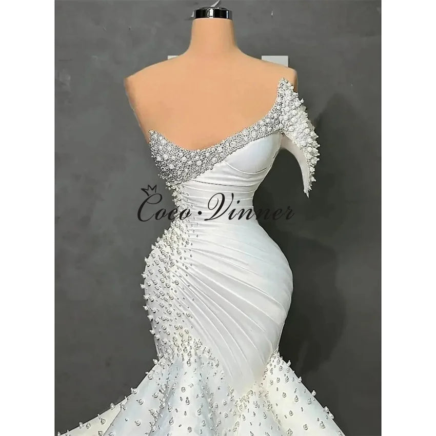 Customized One Shoulder Sleeveless Luxury Mermaid Wedding Dresses 2026 Pearls Beading On Satin Ruffle Wedding Dress Africa W1550