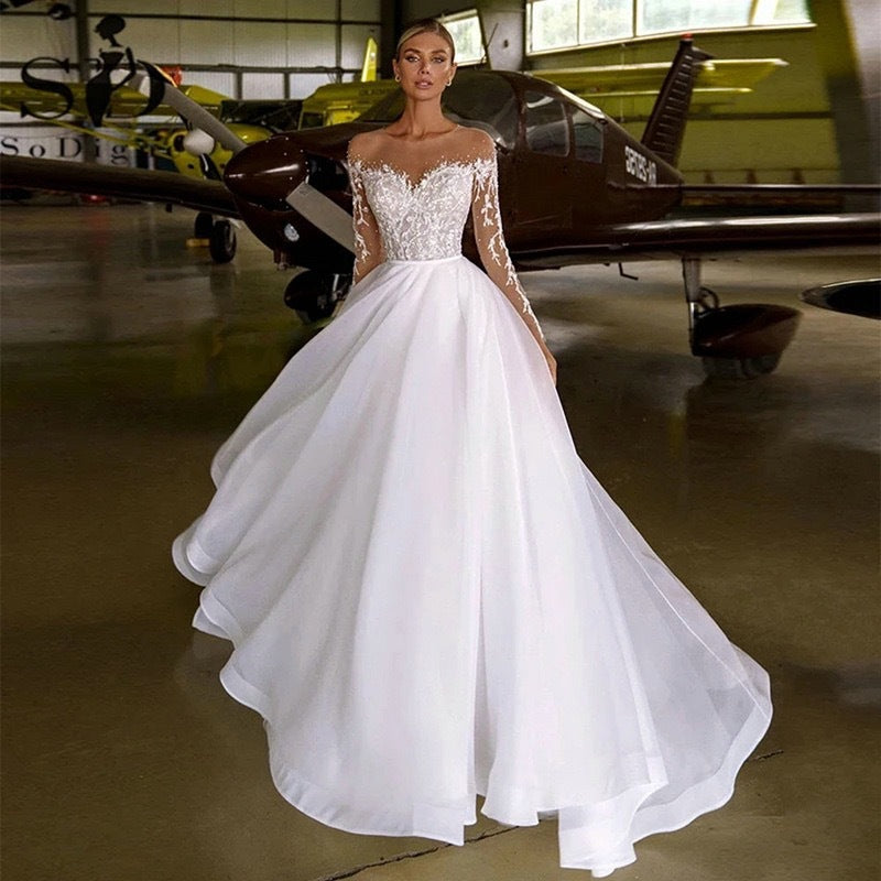 Vestido de novia con mangas largas bordadas y hombros descubiertos